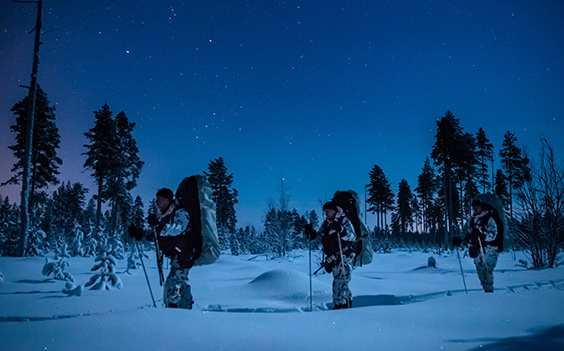 Soldiers ski in deep snow in the dark