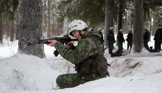 A soldier shooting with an assault rifle in a winter forest.