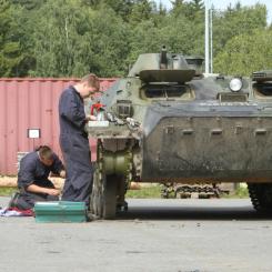 Varusmiehet korjaavat panssarivaunua siniset haalarit päällä