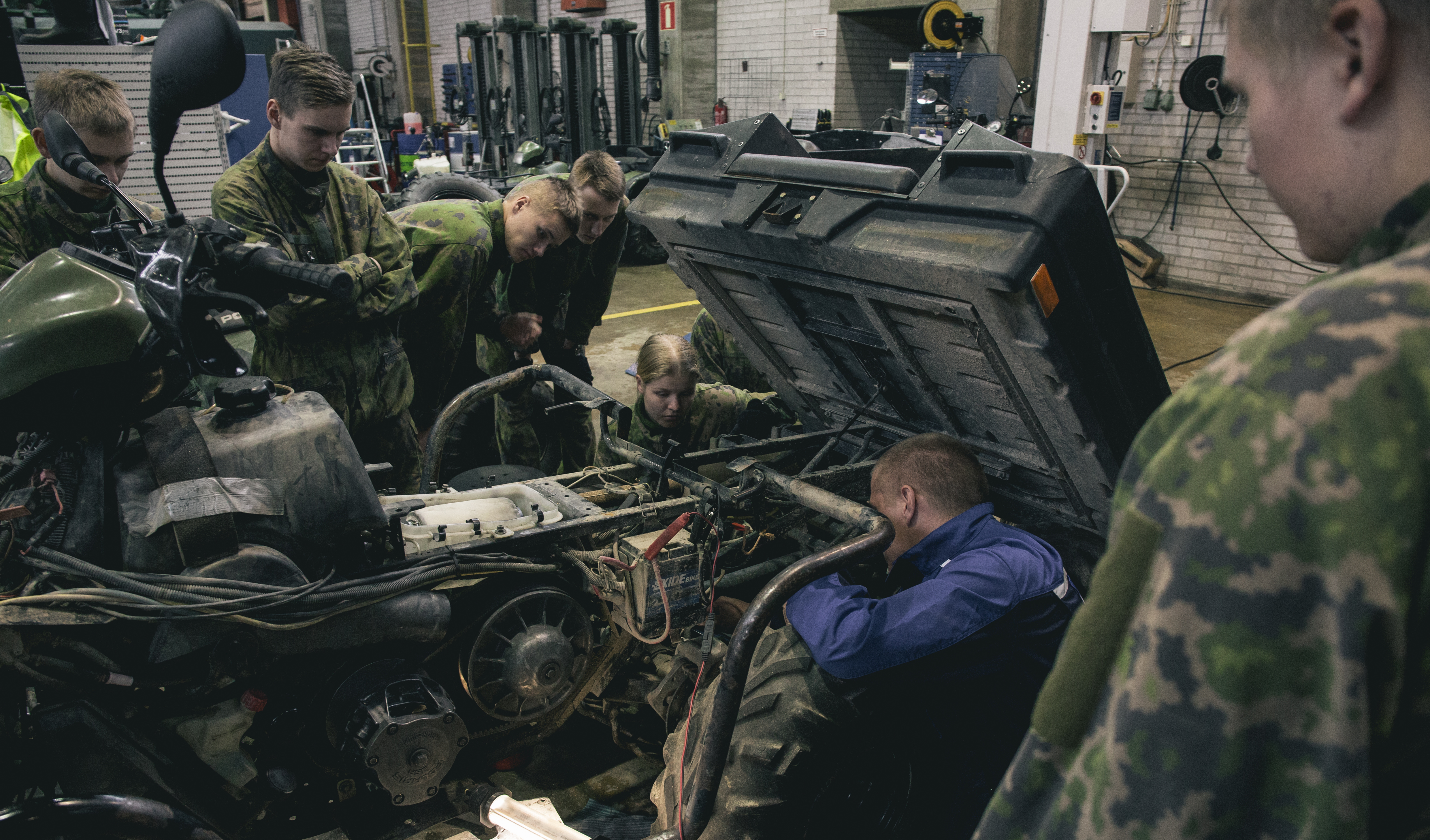 The man trains soldiers for quad bike maintenance by showing points of a dismantled quad bike.