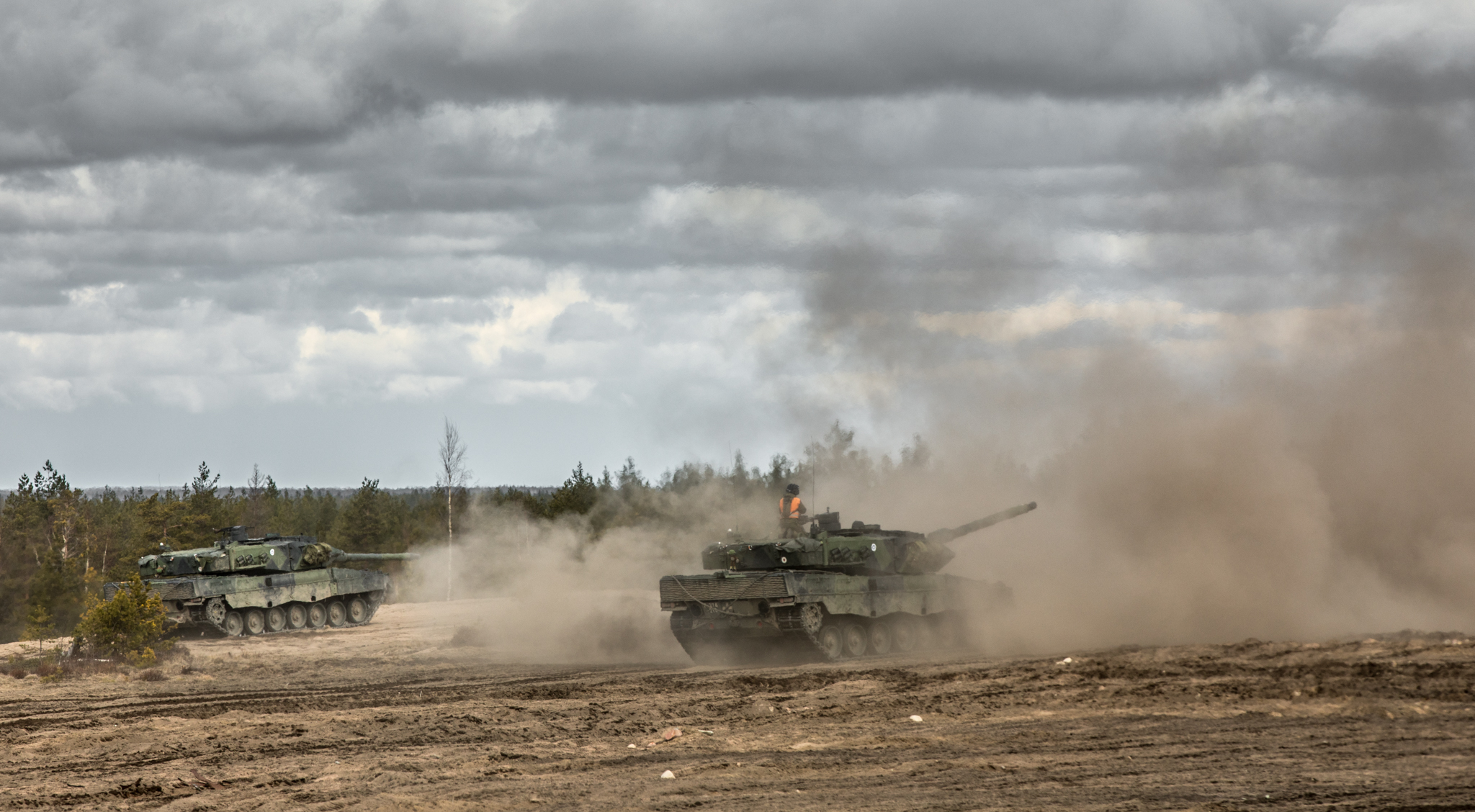 Leopard tanks shoot and there is smoke in the air