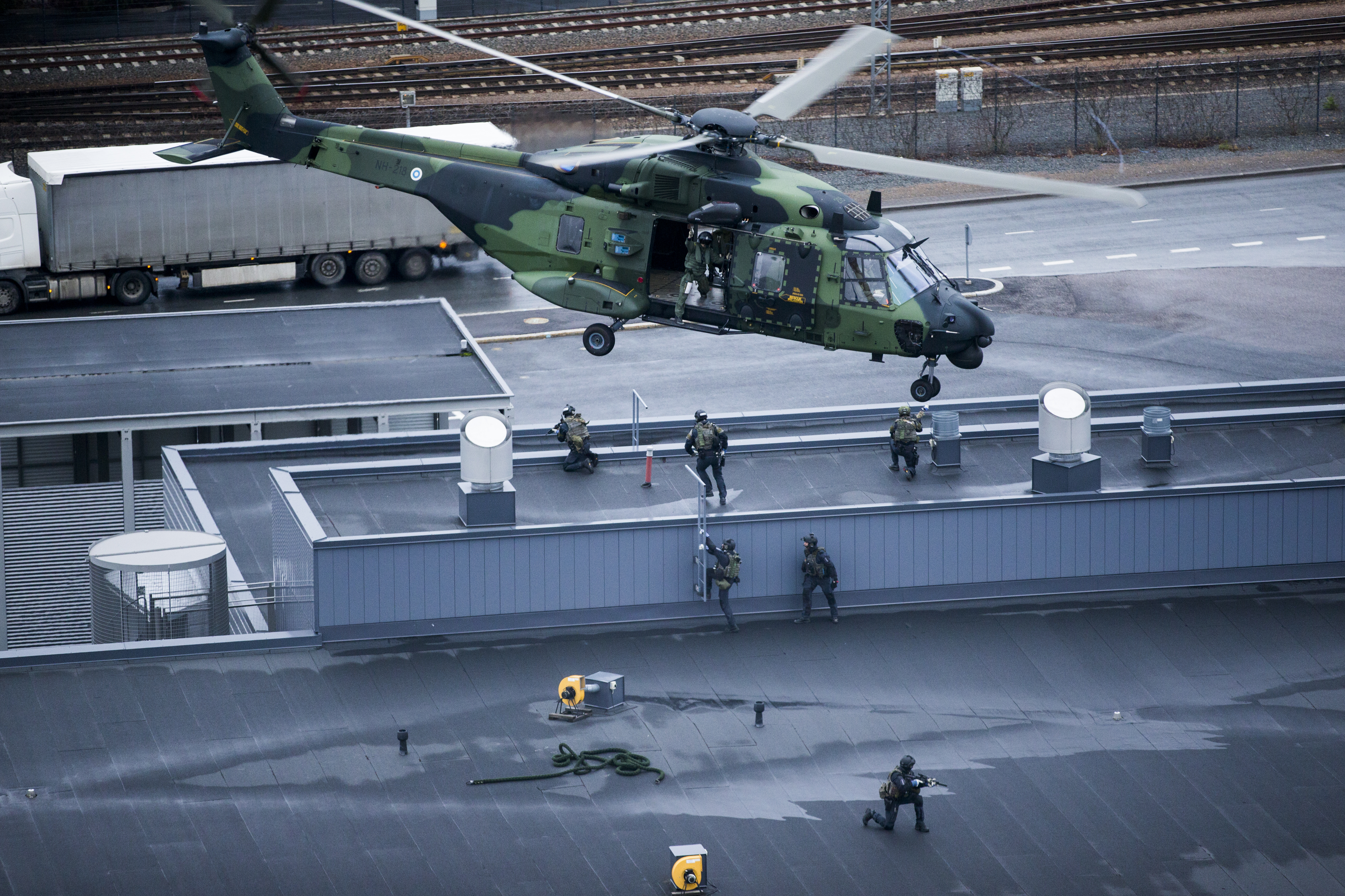Helikopteri rakennuksen katon yllä. Katolla on sotilaita.
