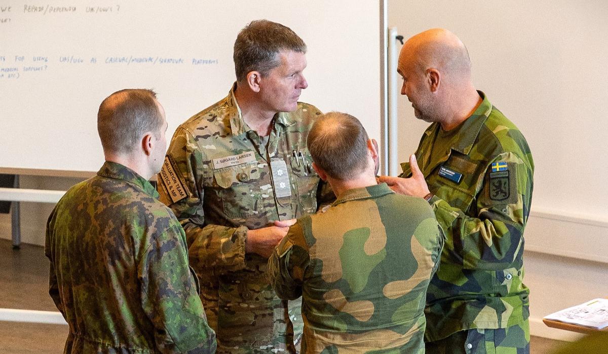 A Finnish, Danish, Norwegian and Swedish soldier are having a discussion.