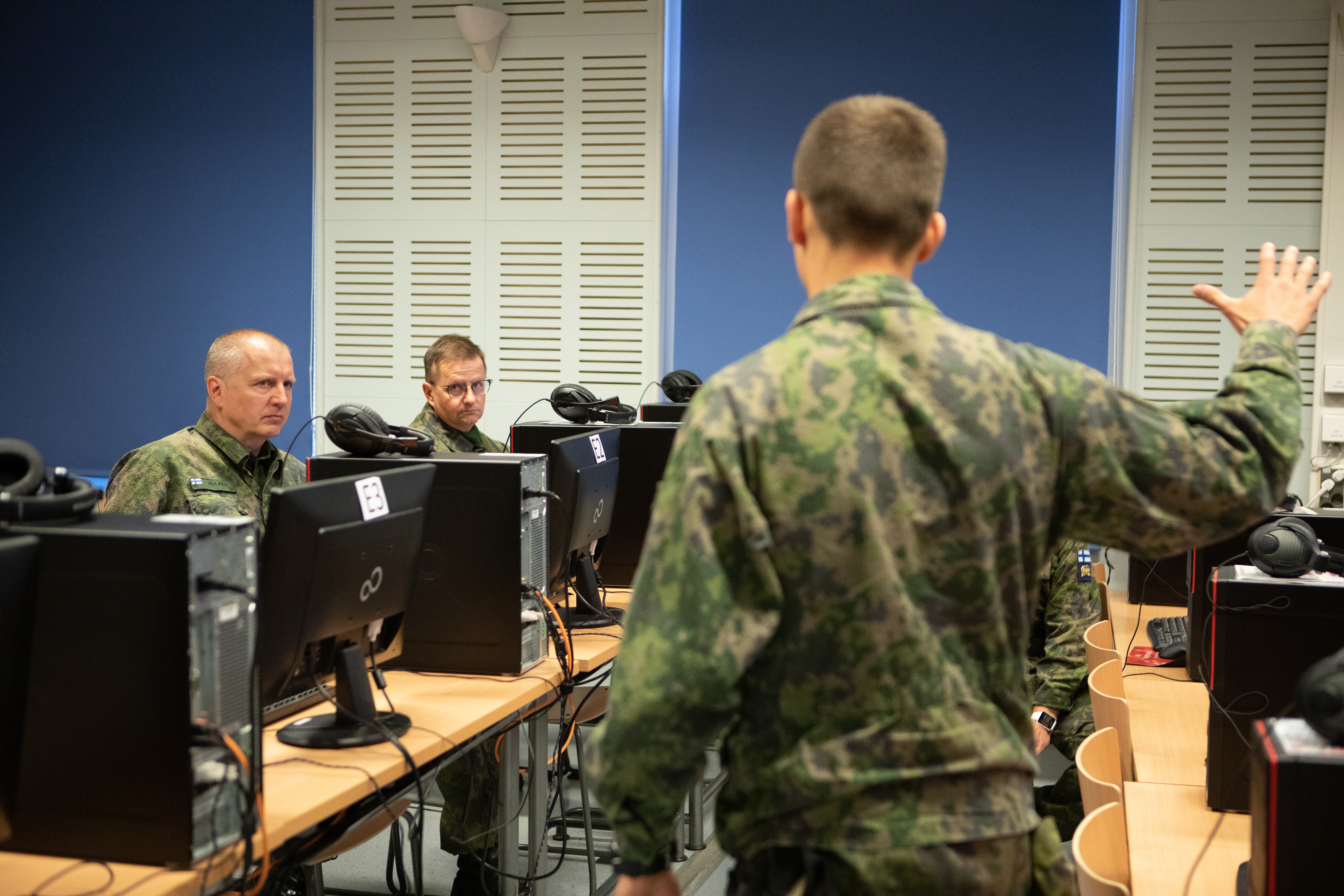 Virtuaalinen koulutusympäristö RUK:ssa, Maavoimien komentaja HUlkko istuu tietokoneen ääressä ja sotilaskouluttaja esittelee virtuaalista koulutusympäristöä.