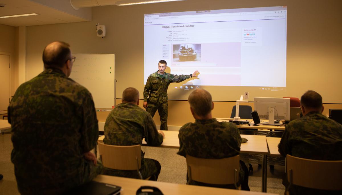 Luokkahuoneessa sotilaskouluttaja esittelee PV-Moodle-oppimisympäristöä.