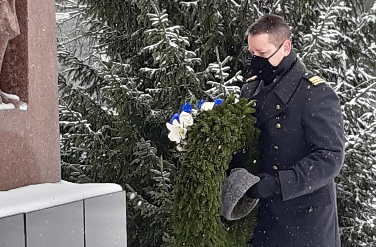 Sotilas laskemassa seppelettä talvisessa lumisateessa.