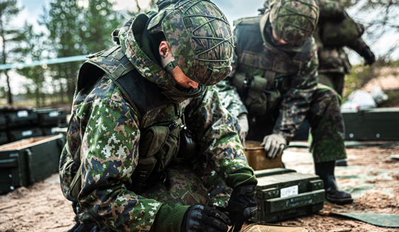 Kaksi varusmiestä avaavat ammuslaatikoita taisteluvälinepaikalla.