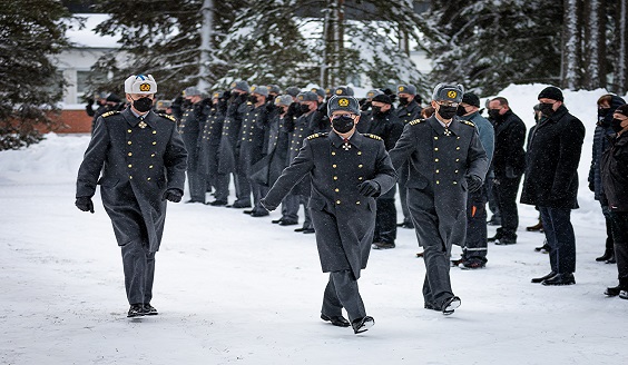 Sotilaallinen vaihtokatselmus. Kolme korkea-arvoista upseeria juhlapuvuissa astelee tarkastamassa rivissä olevia joukkojaan. Lunta ripotteleee talvisessa maisemassa.