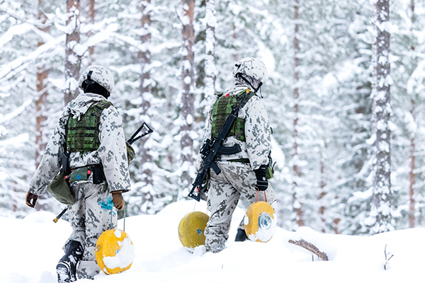 Sotilaita kantamassa telamiinoja talvisessa metsässä.