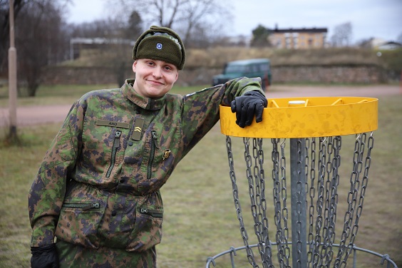 Varusmies nojaa rennosti frisbee-golf-maaliin.