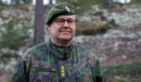 Lähikuva Ilmatorjunnan tarkastajasta, takana metsäinen maisema.