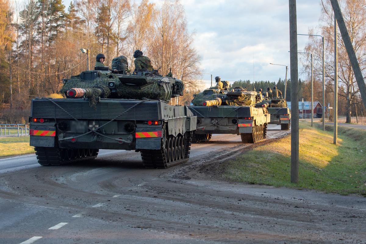 Kolme panssarivaunua ajamassa jonossa maantiellä.