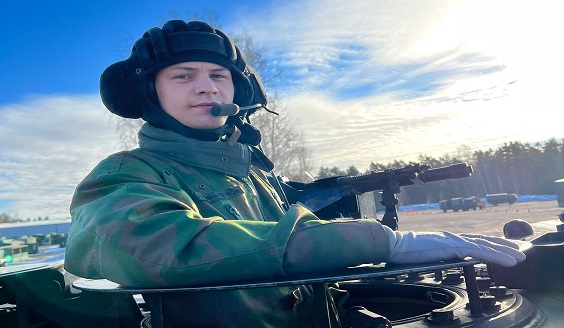 Kadetti panssarivaunussa ja sinistä taivasta vasten, hymyileä sotilas 