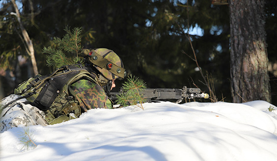 Taistelija tähtää aseella lumimaastossa