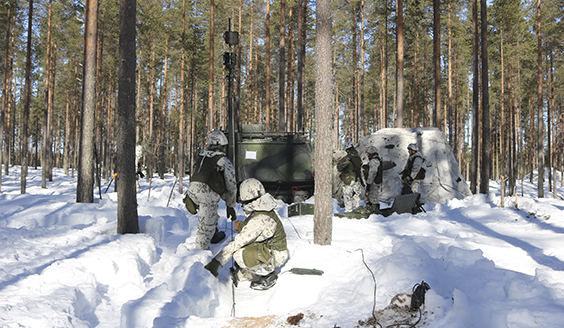 Soldiers setting up an antenna in a snowy forest.