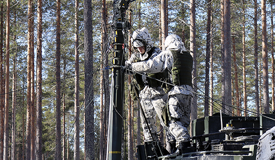 Soldiers setting up an antenna from the top of a vehicle