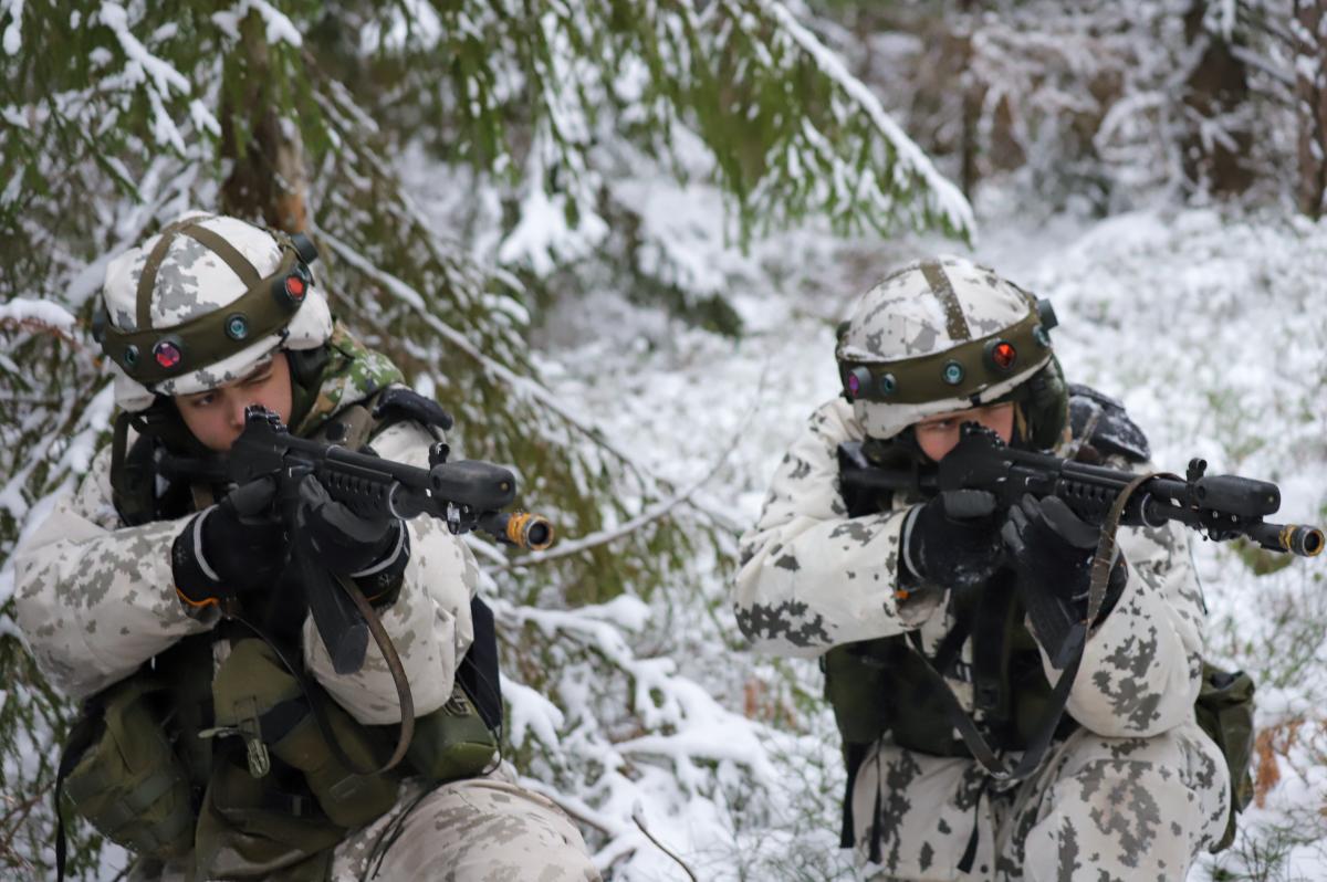 Kaksi lumipukuista sotilasta tähtää rynnäkkökivääreillä lumisessa maastossa.