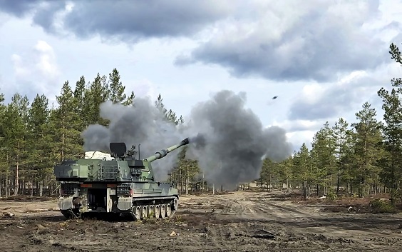 K9 Moukari ampuu maastossa, kuula lentää taivasta kohti.