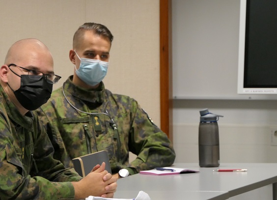 Kaksi maastopukuista sotilasta pöydän ääressä oppitunnilla.