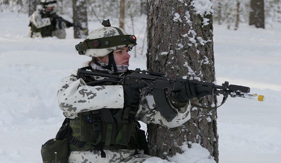 Lumipukuinen sotilas aseen kanssa lumisessa maastossa.