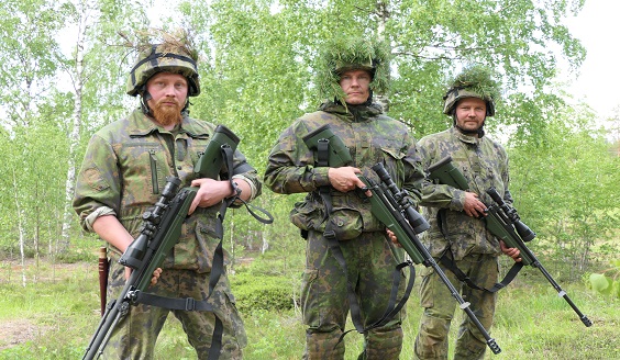 Kolme maastopukuista sotilasta, reserviläistä, tarkkuuskiväärit kädessä rivissä seisomassa.