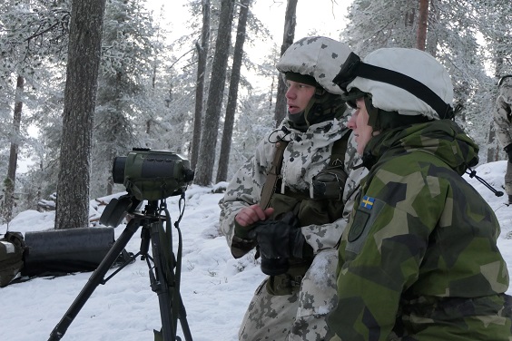 Ruotsalainen sotilas maastopuvussa ja suomalainen sotilas lumipuvussa tulenjohtopaikalla mittalaitteella.