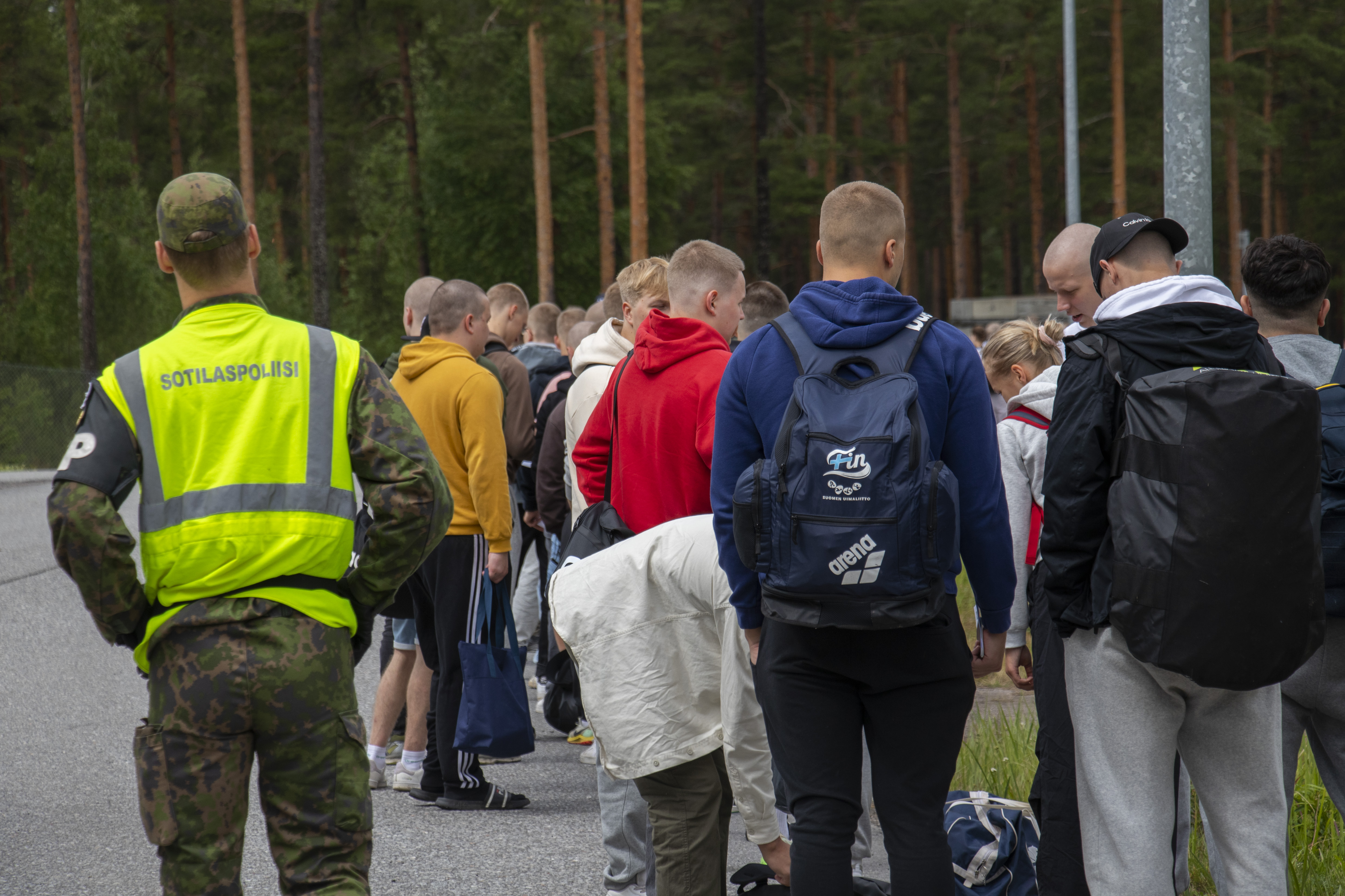 Sotilaspoliisi tarkkailee palveluksen aloittavaa siviilipukeista joukkoa