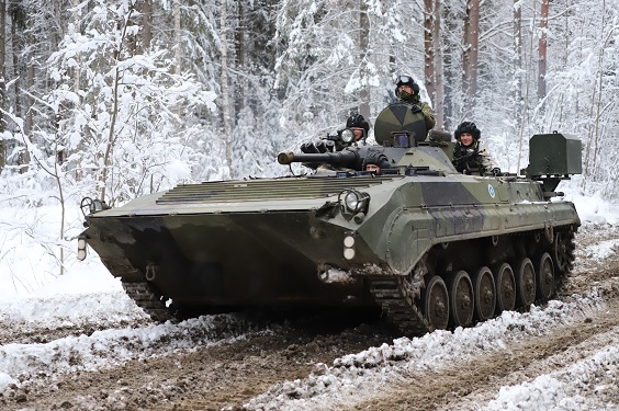 Panssarivaunussa kolme sotilasta lumisessa maisemassa.