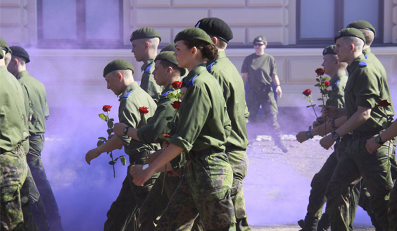 Reserviupseerikurssin 248 ruusurynnäkkö, varusmiehet kävelevät riveissä ruusut käsissään, taustalla violettia savua