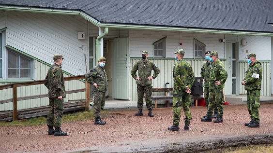 Suomalaisia ja ruotsalaisia sotilaita seisomassa ringissä, kaikilla maskit kasvoilla.