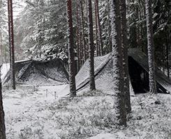 Kaksi telttaa seisoo lumisessa metsässä.