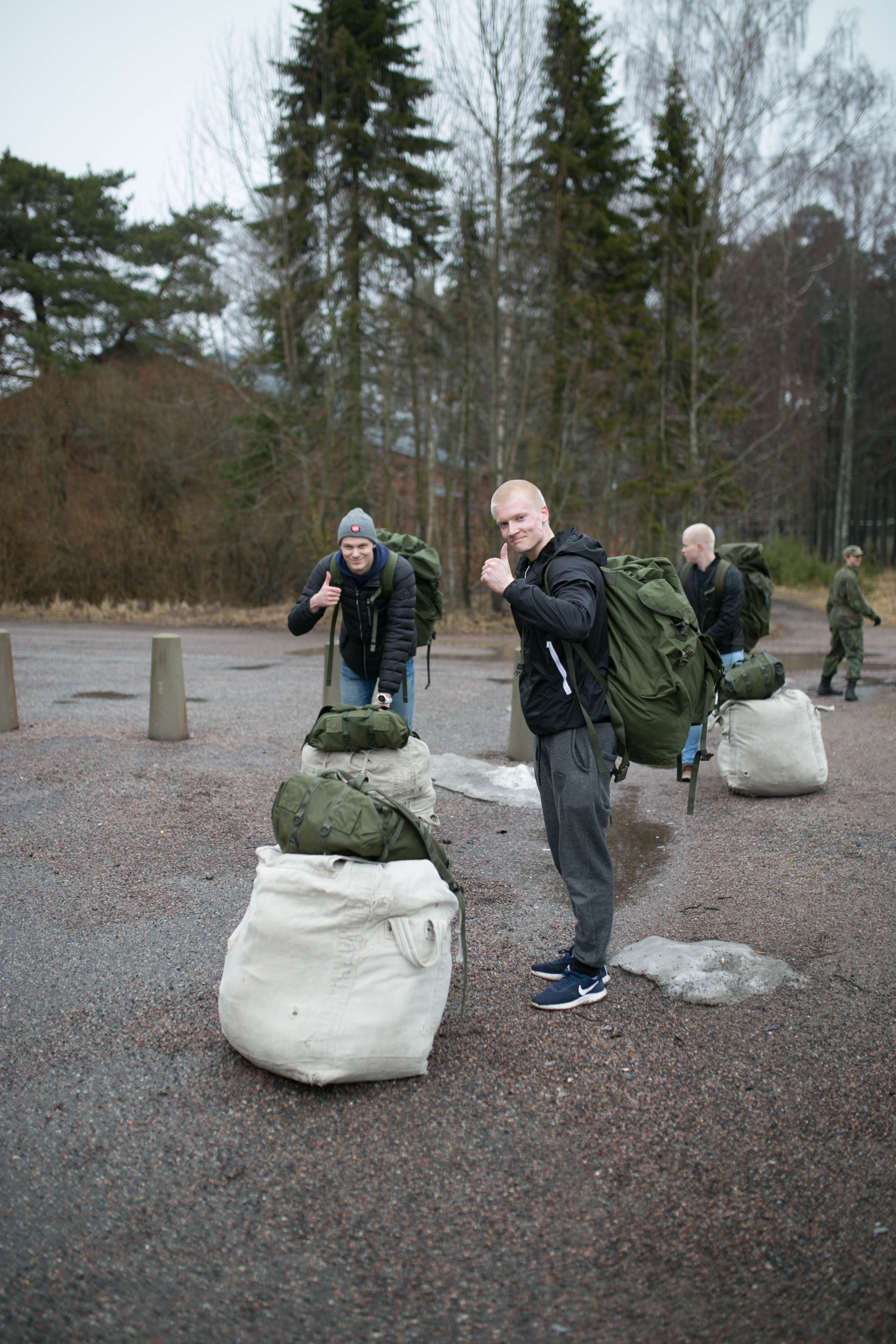 Miehet kantavat varustesäkkejä ja näyttävät peukkua