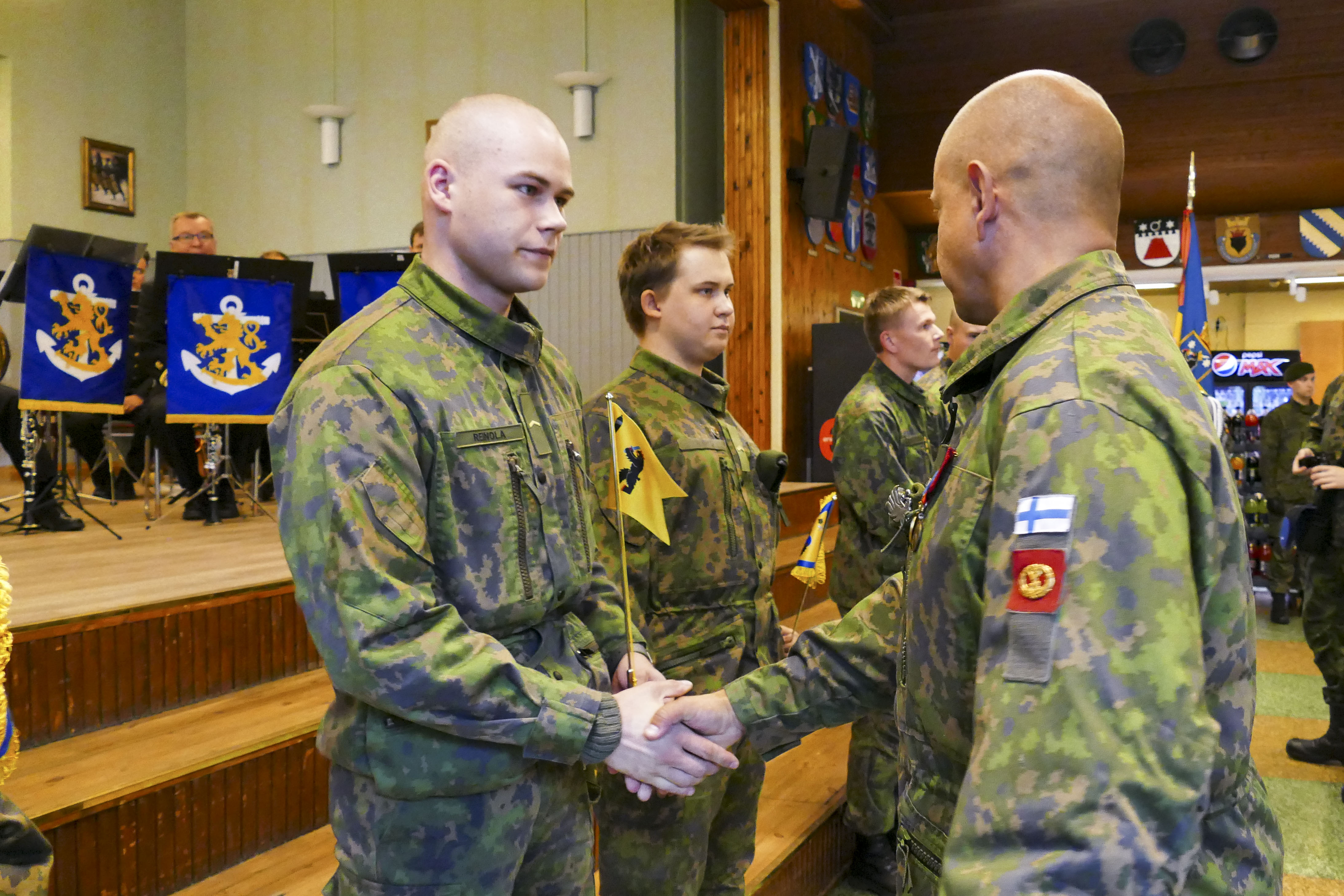 Upseeri kättelee sotilaita joilla on käsissään viirit