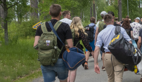 Kuvassa kotiutuvia varusmiehiä selin kameraan ja siviilit päällä kävelemässä ulos varuskunnasta.