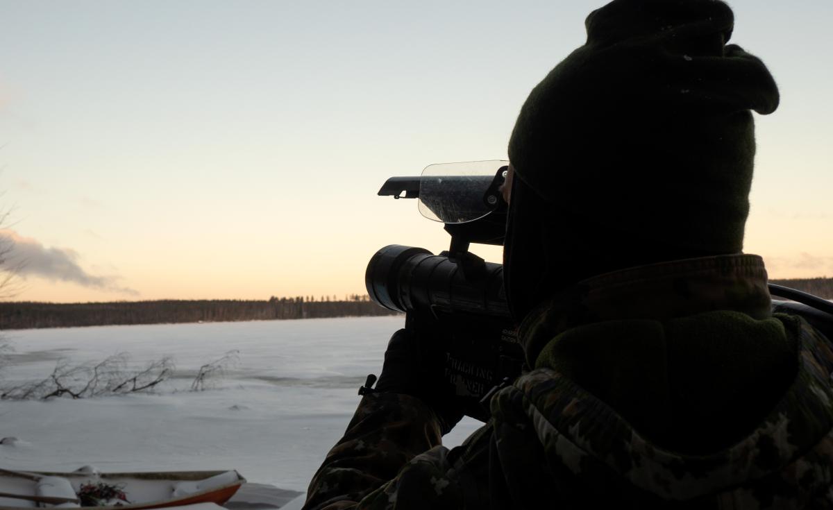Sotilas seisoo jäätyneen järven rannalla ja osoittaa ilmatorjuntaohjuksella kohti taivasta.