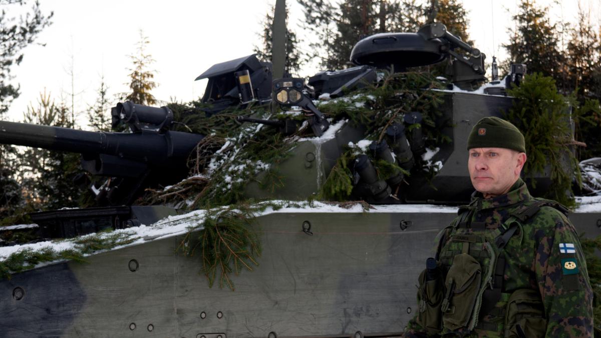 Kenraali seisoo panssarivaunun rinnalla, katsoo eteenpäin hieman ohi kamerasta