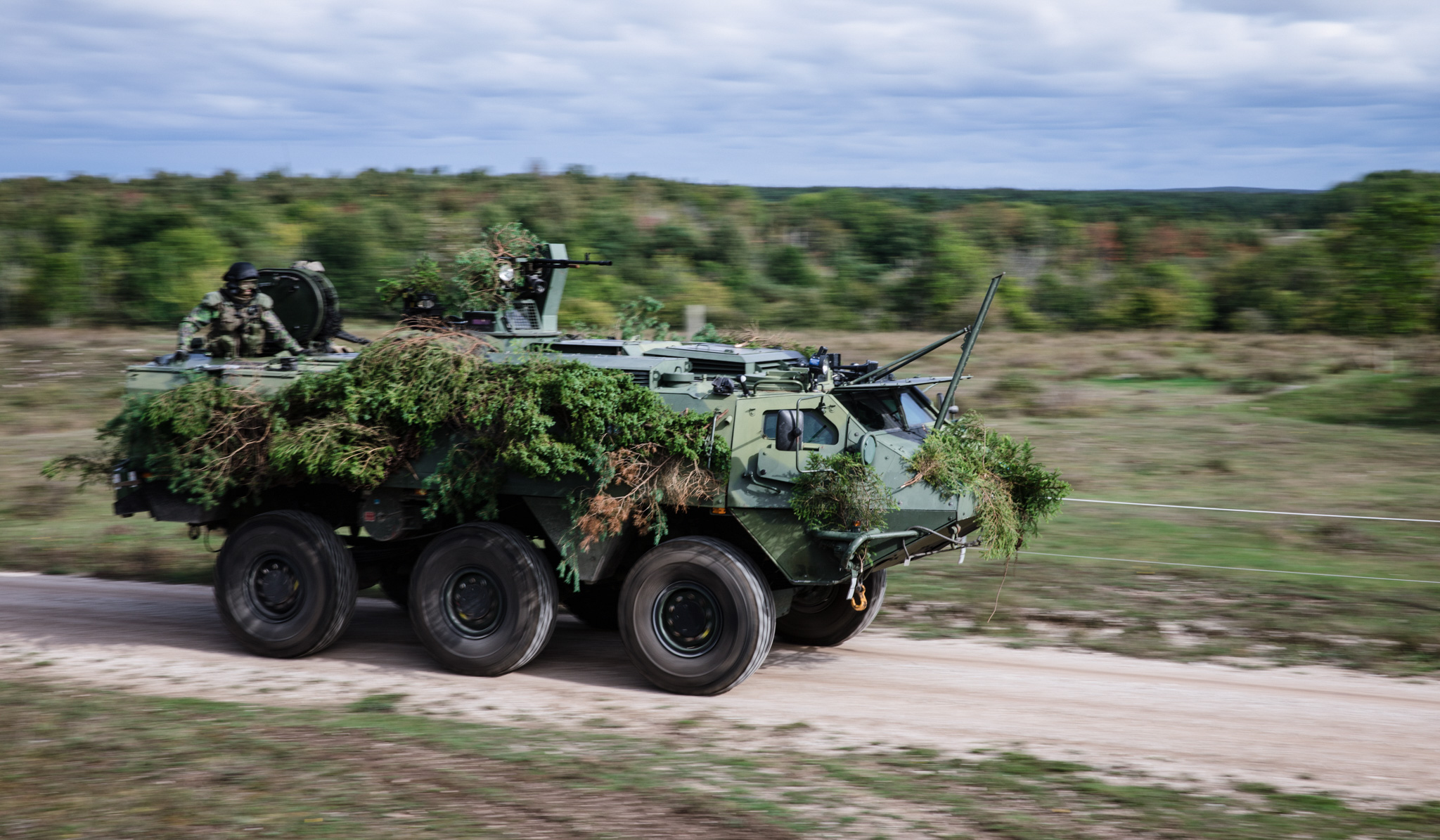 A camouflaged tank drives on the road