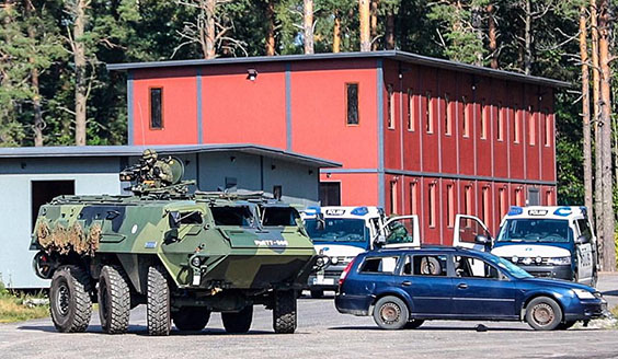 Sotilaat suojaavat panssariajoneuvolla poliisipartioita viranomaisyhteistyöharjoituksessa rakennetulla alueella