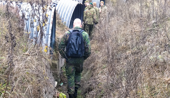 kuva, jossa suomalainen sotilas kävelee maastossa kohti ukrainalaisia sotilaita