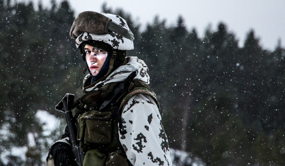 kuva, jossa talviseen maastopukuun pukeutunut sotilas katsoo kameraan