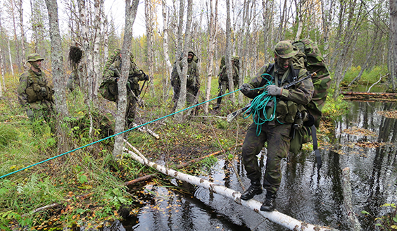 Soldaten korsar floden med hjälp av avverkat trä och rep