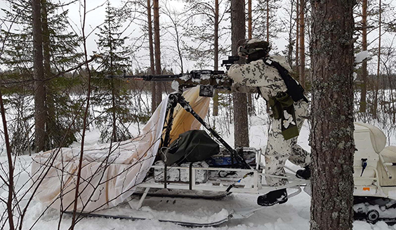 The soldier aims with a machine gun from the platform behind the snowmobile