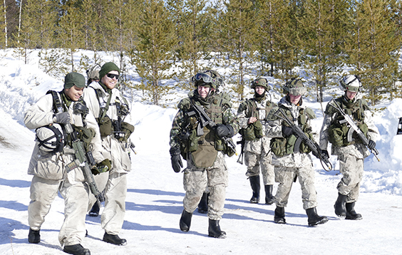 Soldiers walk in combat gear and laugh