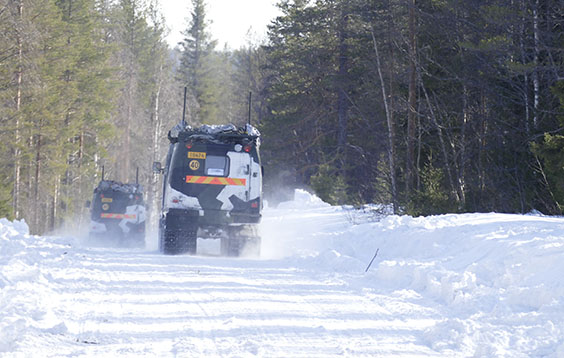 Tracked vehicles drive on a snowy forest road