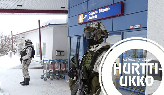 Taisteluvarustukseen pukeutuneet varusmiehet suojaavat lentokenttäterminaalin ulko-ovea talvella.