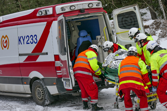 Ensihoitajat työntävät paareilla makaavaa henkilöä ambulanssiin.