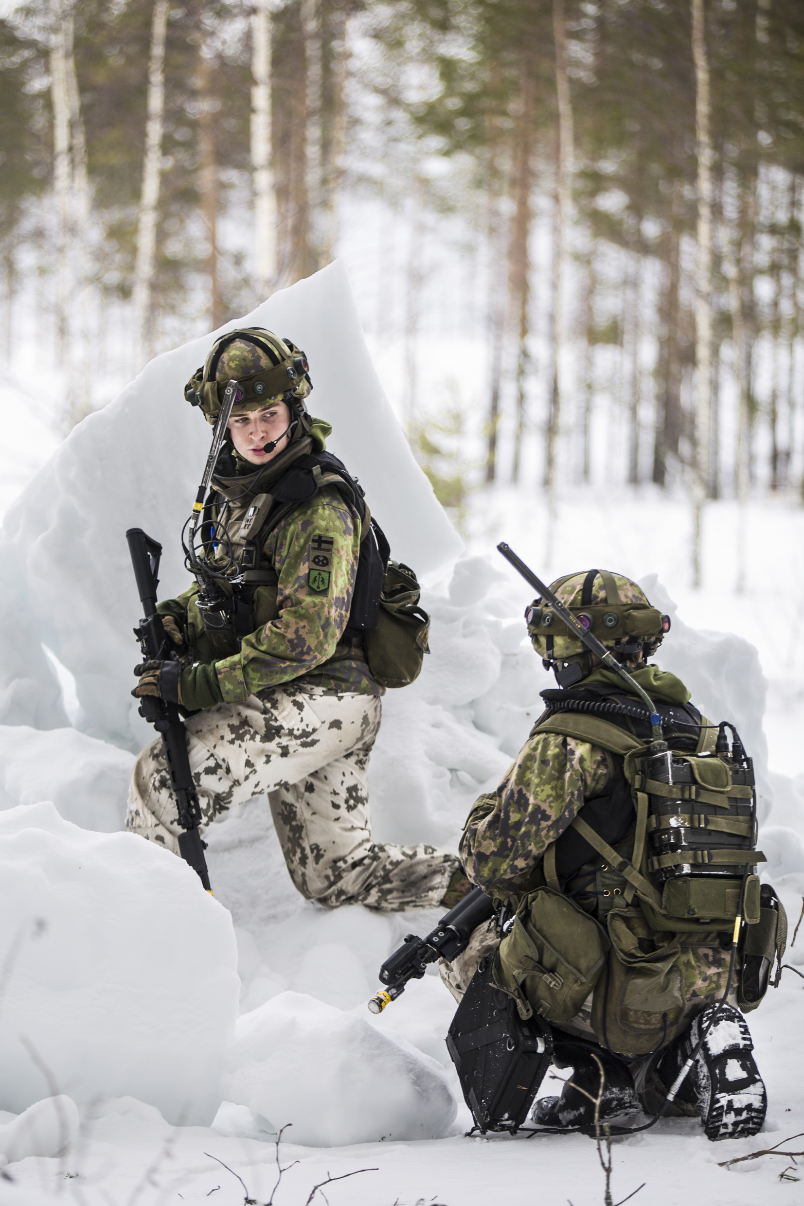 Kaksi sotilasta lumessa korkeassa polviasennossa, toinen kääntyneenä katsomaan toista.