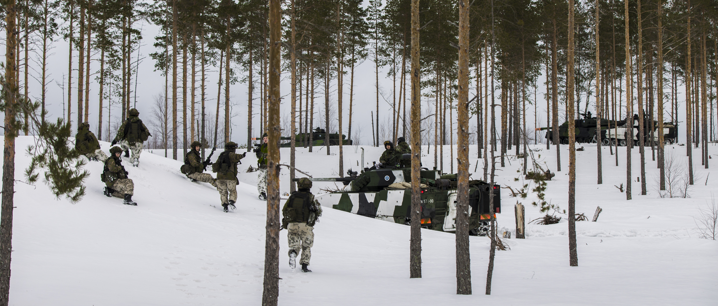 Sotilaita ja panssarivaunuja lumisessa metsässä
