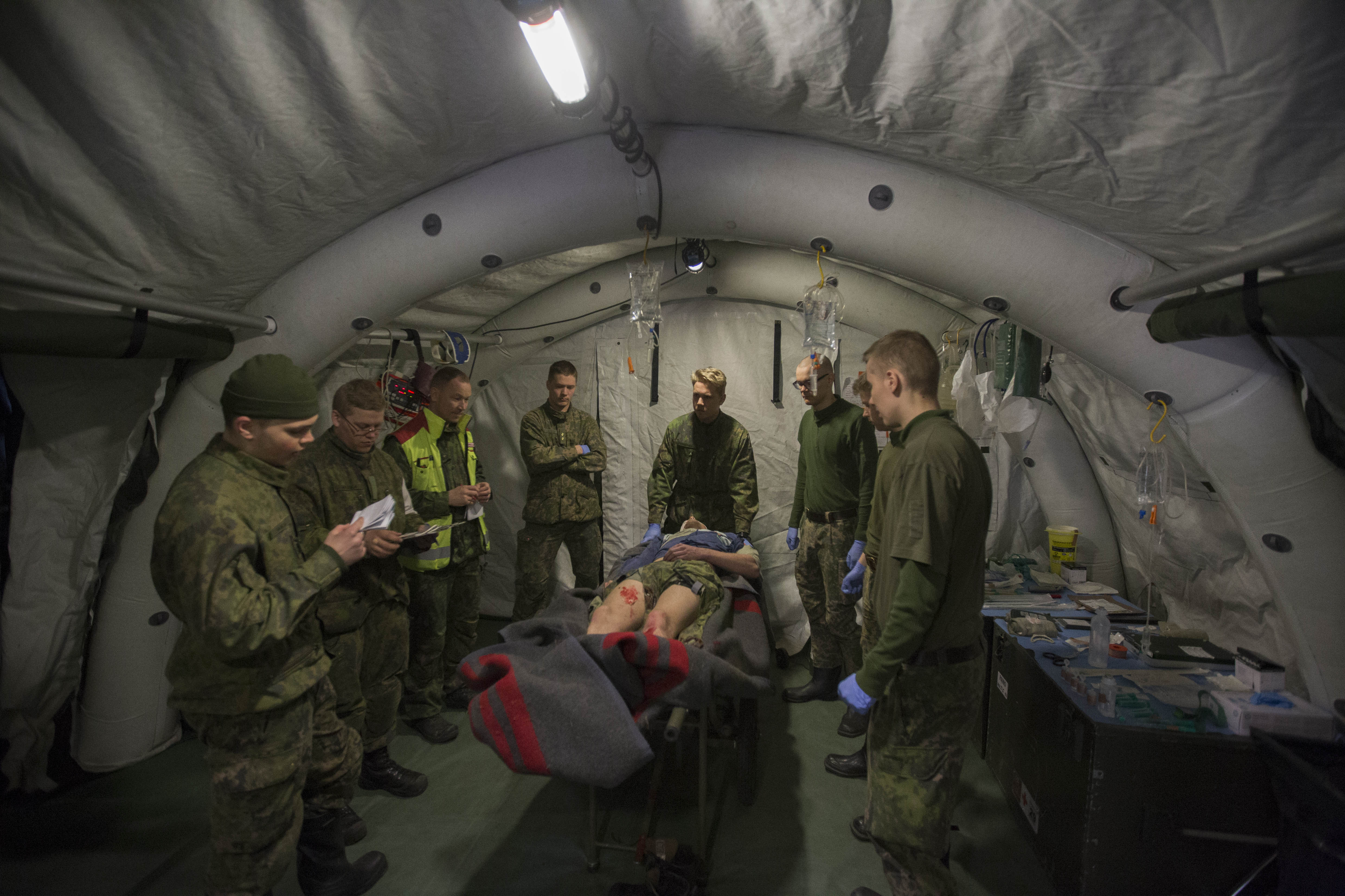 Sotilaat teltassa potilaan ympärillä