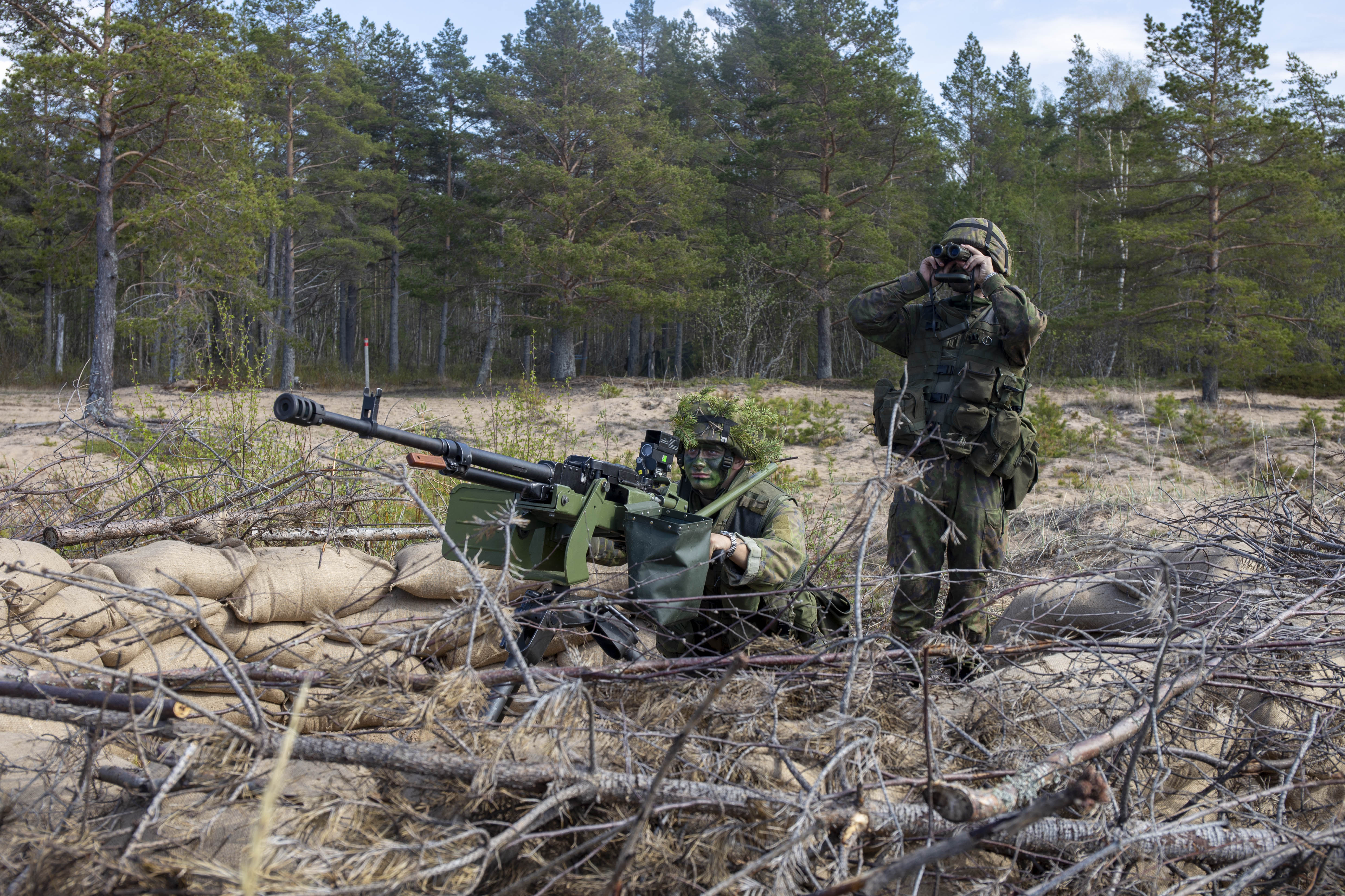 Sotilas tähtää ilmatorjuntakonekiväärillä ja toinen sotilas tähystää kiikareilla